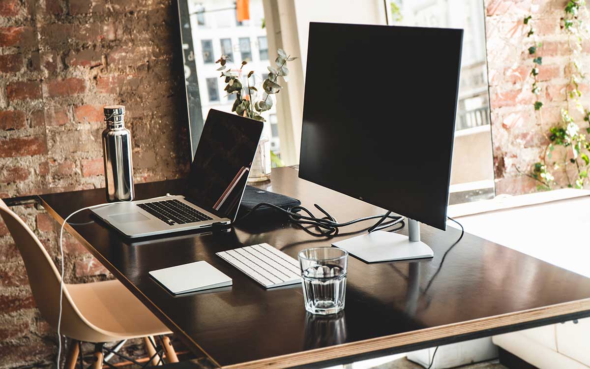 Computer screen and laptop on desk in home office