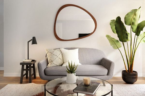 Airy living room with a curves, light grey sofa and circular wooden mirror. 