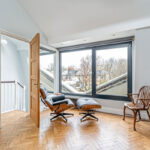 Room in a double pitched mansard loft conversion with arm chair and large window